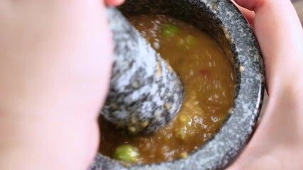 Close up of cooking Spicy Shrimp Paste Chili Sauce in the stone mortar, favorite Thai food (Nam Prik Ka Pi)