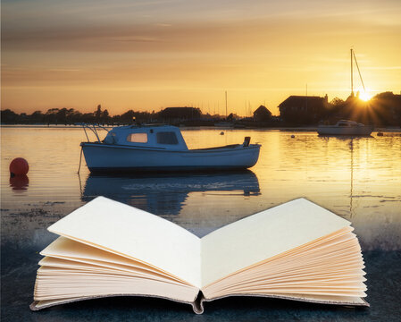 Beautiful Summer sunset landscape over low tide harbor with moored boats coming out of pages of inaginary book