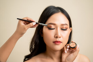 Fototapeta premium Makeup artist applied eyeshadow on the face of a beautiful Asian woman