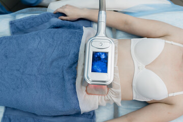 Woman getting cryolipolysis fat treatment procedure in professional cosmetic cabinet or spa center,...