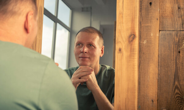 Happy smiling mature man looking at his mirror reflection. Healthy self-esteem and age perception