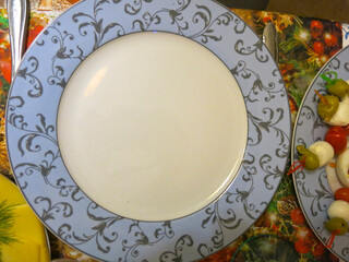 empty beautiful plate with a blue border on the festive table waiting for the dishes