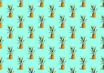 Seamless pattern of many ripe pineapples isolated on green background. Top view. Tropical fruit summer exotic concept.