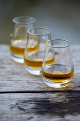 Tasting glasses of scotch whisky strong drink on old outdoor wooden table