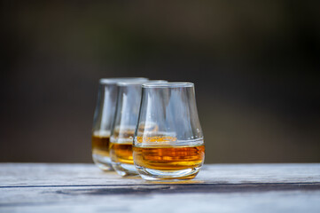 Tasting glasses of scotch whisky strong drink on old outdoor wooden table