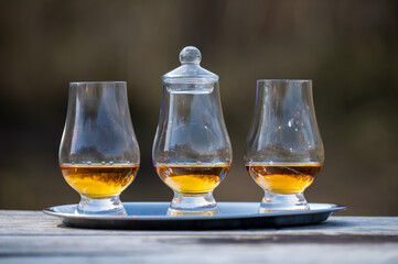 Tasting glasses of scotch whisky strong drink on old outdoor wooden table