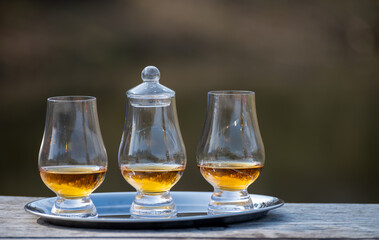 Tasting glasses of scotch whisky strong drink on old outdoor wooden table
