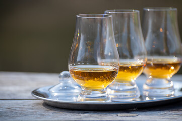 Tasting glasses of scotch whisky strong drink on old outdoor wooden table