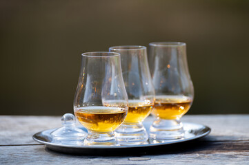 Tasting glasses of scotch whisky strong drink on old outdoor wooden table