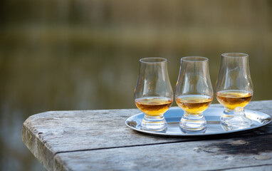 Tasting glasses of scotch whisky strong drink on old outdoor wooden table