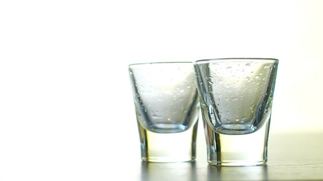 strong alcohol pouring into shot glasses on white background