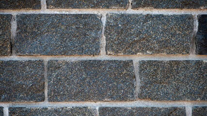 Wall of stones. Brick wall. Gray background with black geometric patterns, of rectangular stones, bricks. Part of a stone wall pattern for background, texture or text. rough grainy stone wall