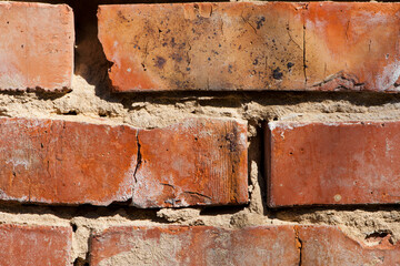 old brick wall. Decorative wall made of destroyed dark red bricks. Background for design on a construction or architectural theme. cracked cement joint. red brick close up. may use to interior design