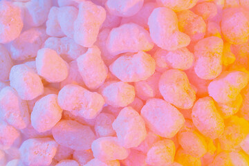 Corn sticks in sugar powder. Sweet food background. Corn sticks in mixed colorful creamy pink and yellow light. Crispy, sweet and fun snack for party and movie time