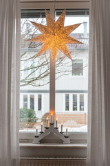 Decorative Christmas lantern star lamp and lamp with candles or candle bridge on a window, winter...