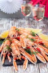 Sea crayfishes on a stone plate served with dill and lemon, festive decoration and glass of schnapps, vertical