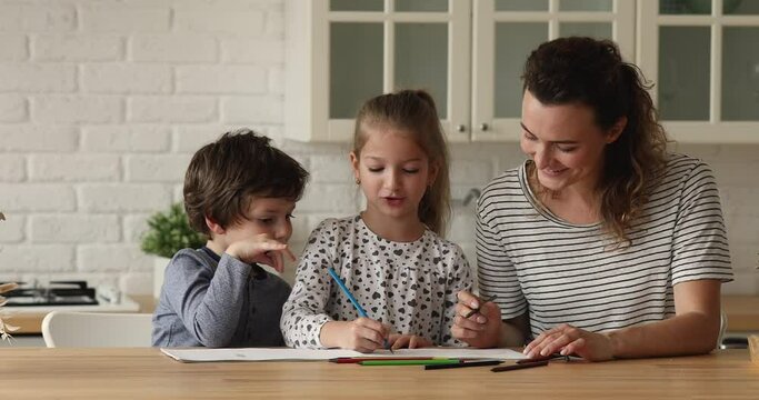 Family drawing together with colorful pencils at sketchbook. Loving mother teach little son and daughter, spend time in cozy kitchen with children enjoy weekend at home. Develop skills, hobby concept