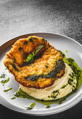 schnitzel with mashed potatoes and pesto sauce on plate