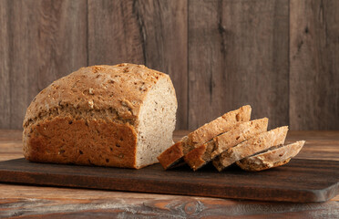 Homemade wholegrain sliced bread on a dark wooden table. Organic bread baked at home from wheat flour.