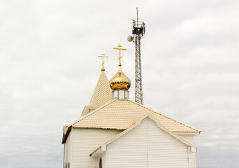 A Christian church and a 5G mobile tower. A radio tower near the golden domes.