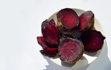 Beet halves and slices on a plate. White background. Copy space.