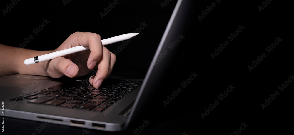 Poster man using stylus pen on laptop or notebook working at home in the at night for web banner with copy 