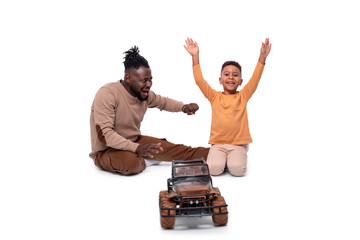 Dark skinned African male and his little son have fun with a toy car  together, isolated