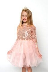 Studio shot of  attractive little girl wearing pink ball gown and crown posing against white background in studio