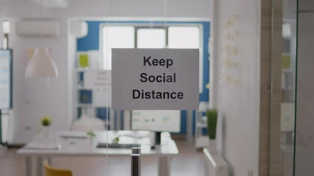 Keep Social Distance sign on glass wall in empty office during covid 19 coronavirus pandemic. Business workplace interior with nobody in it, economy crisis