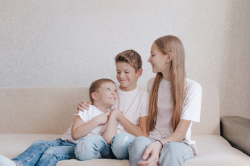 friendly happy children a girl and two boys are sitting on the sofa smiling looking at each other