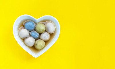 Black sesame dumpling in ginger tea recipes on yellow background.