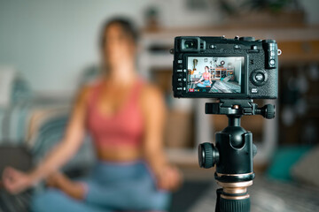 Young woman exercising at home doing pilates and recording at her with digital camera to teach workout and produce web class - content creator business free healthy lifestyle people concept