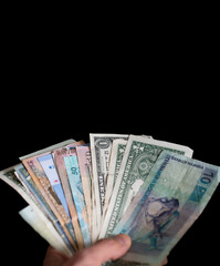 Hand holding different kind of bills over black