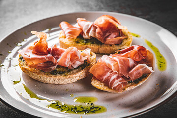 Bruschetta with prosciutto and pesto sauce on plate