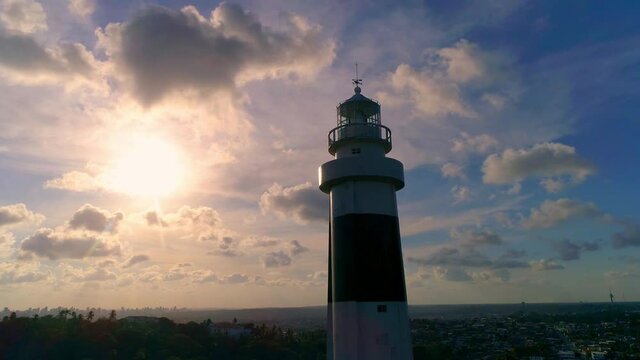 Aerial image surrounding Olinda lighthouse with sunset in the background and drifting towards blue sky with clouds