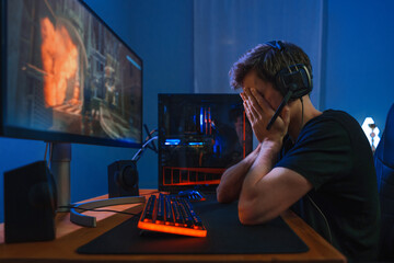 Young caucasian esport gamer wearing headphones feel painful and upset because of losing online...