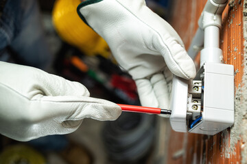 Top view. Electrician worker at work with screwdriver installs the switches of a residential electrical system. Working safely with protective gloves. Construction industry. 