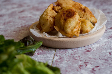 Fried battered cod with salad on the pink background.