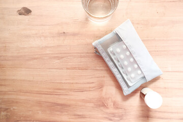 top view of pills of blister pack in a small bag on wooden background 