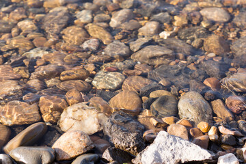 River stones lie at the bottom under the clear water in the river.