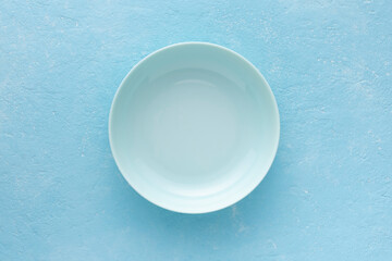 Empty blue plate on a light blue background.