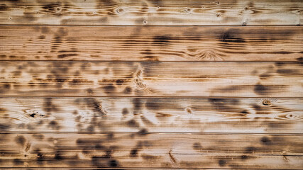 Light wood texture. Charred and burnt old boards with knots. Close-up texture of wide burnt board, panoramic banner