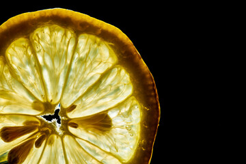 Lemon slice against light with black background.