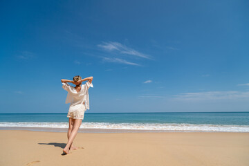 Happy young woman relax on the beach, arms raised up to sky.