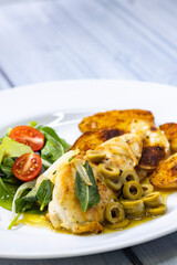 chicken breast baked on sage with green olive sauce with salad and potatoes