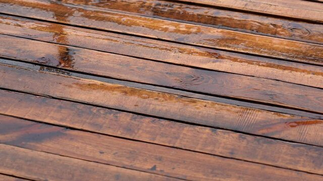 Pouring rain outdoors. Texture of wet wooden brown floor of patio or terrace and rain drops falling down 