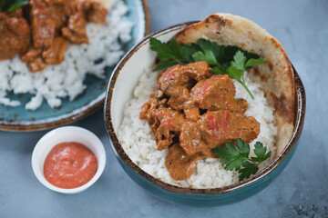 Bowl of indian butter chicken or Murgh Makhani, studio shot on a grey concrete background, selective focus