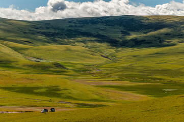 Two SUV off road vehicles reach a pristine green valley in the mountains