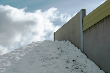 a snow covered slope next to a concrete wall