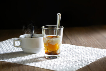 Soft-boiled eggs in clear cup and hot coffee in white cup. Asian breakfast.
